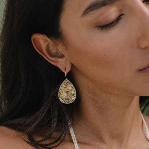 Anna Beck Dotted Grounded Teardrop Earrings ER10699 TWT Close-up of a woman wearing gold teardrop earrings.