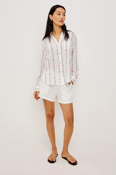 Rails Charli Shirt in Striped Seashells Woman wearing a white blouse with floral patterns and white shorts on a plain background