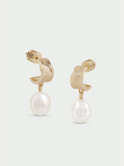 Tutti & Co Freshwater Pearl Earrings in Gold A pair of gold huggie hoop earrings with a textured finish and a dangling white freshwater pearl, shown against a light gray background.