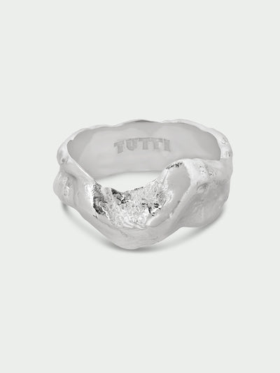 Tutti & Co Forge Ring in Silver A textured silver ring with a sculptural, organic shape and a polished interior engraved with the brand name 'TUTTI', shown on a light gray background.