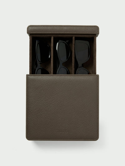 Tutti & Co Contour Glasses Box A dark brown textured leather sunglasses case, shown open to reveal three black sunglasses inside, set against a light gray background.