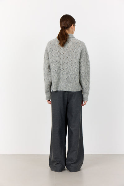 Levete Room Niva 1 Pullover in Light Grey Person wearing a gray patterned sweater and dark pants on a white background