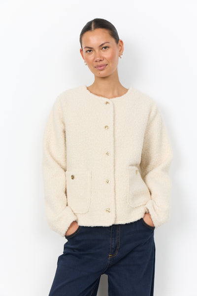Soya Concept Shaima 12 Jacket in Cream 500246 A woman modeling a cream-colored, textured bouclé cardigan with gold buttons and front pockets, paired with dark blue jeans, against a plain white studio background.
