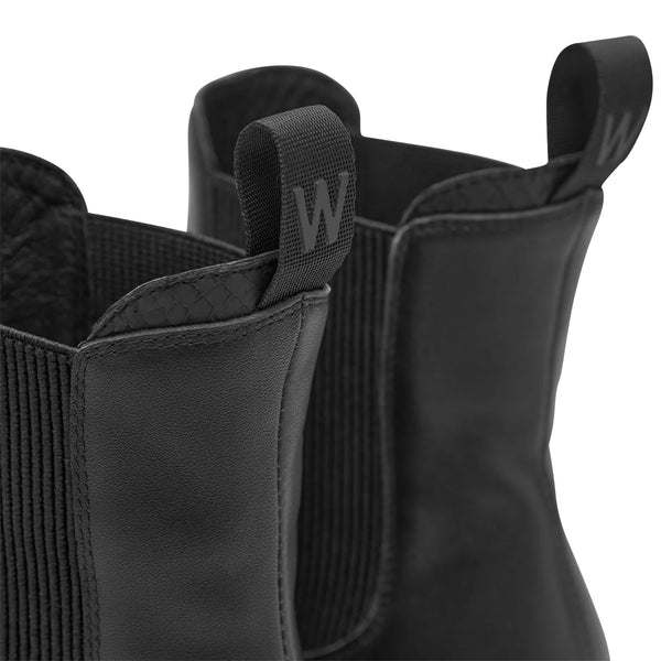 Woden Aya L Boots in Black Close-up of black boots with a brand logo on a white background