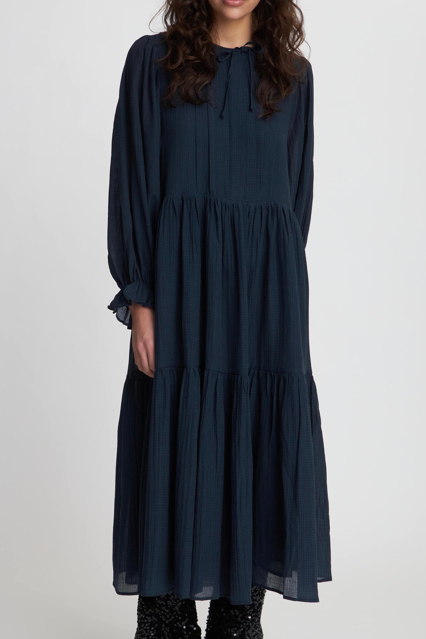 Stella Nova Navy Maxi Dress with long sleeves and a round neck. Created in a beautiful lightweight material. The dress features a hidden half button placket and a string closure. Elastic cuffs create a cute ruffle. Loose fit and a wide skirt.
