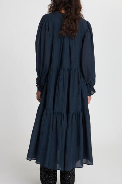 Stella Nova Navy Maxi Dress with long sleeves and a round neck. Created in a beautiful lightweight material. The dress features a hidden half button placket and a string closure. Elastic cuffs create a cute ruffle. Loose fit and a wide skirt.
