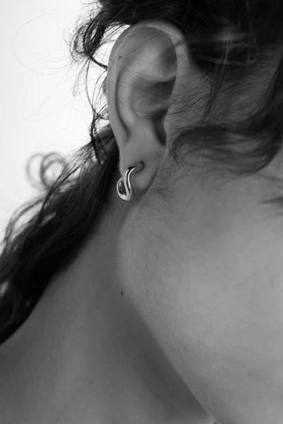 Tutti Small Haze Earrings in Silver Close-up of an ear with a silver hoop earring on a neutral background