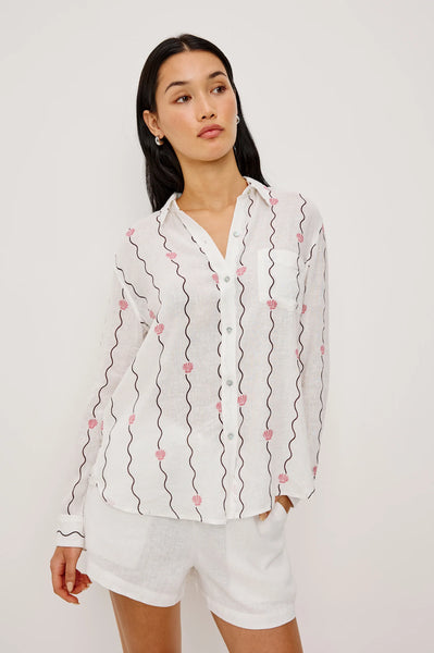 Rails Charli Shirt in Striped Seashells Woman wearing a white blouse with pink floral embroidery on a plain background