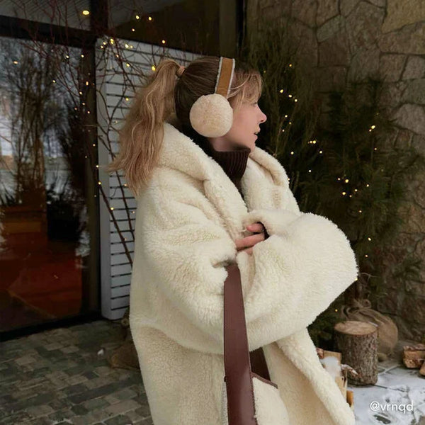 Emu Australia Angahook Earmuffs in Chestnut W9403 Person wearing a white fur coat and cream ear muffs in a cozy outdoor setting.