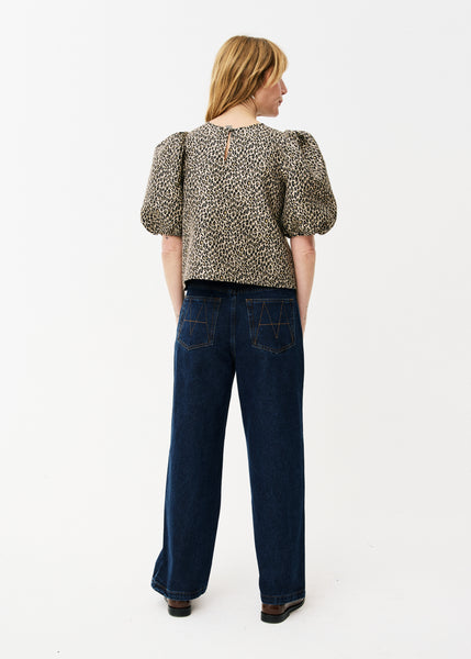 Maison Anana Emira Blouse in Leopard Woman wearing a leopard print top and dark blue jeans on a white background