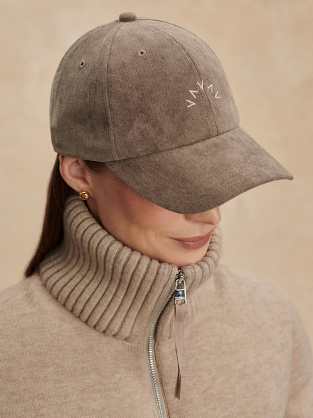 Varley Franklin Cap in Pine Bark Person wearing a brown suede cap with a subtle pattern on a beige background