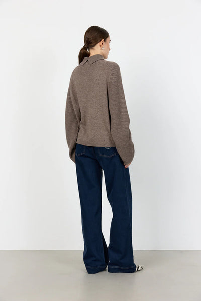 Levete Room Ossy 1 Pullover in Walnut Melan Person wearing a brown sweater and dark blue jeans against a white background